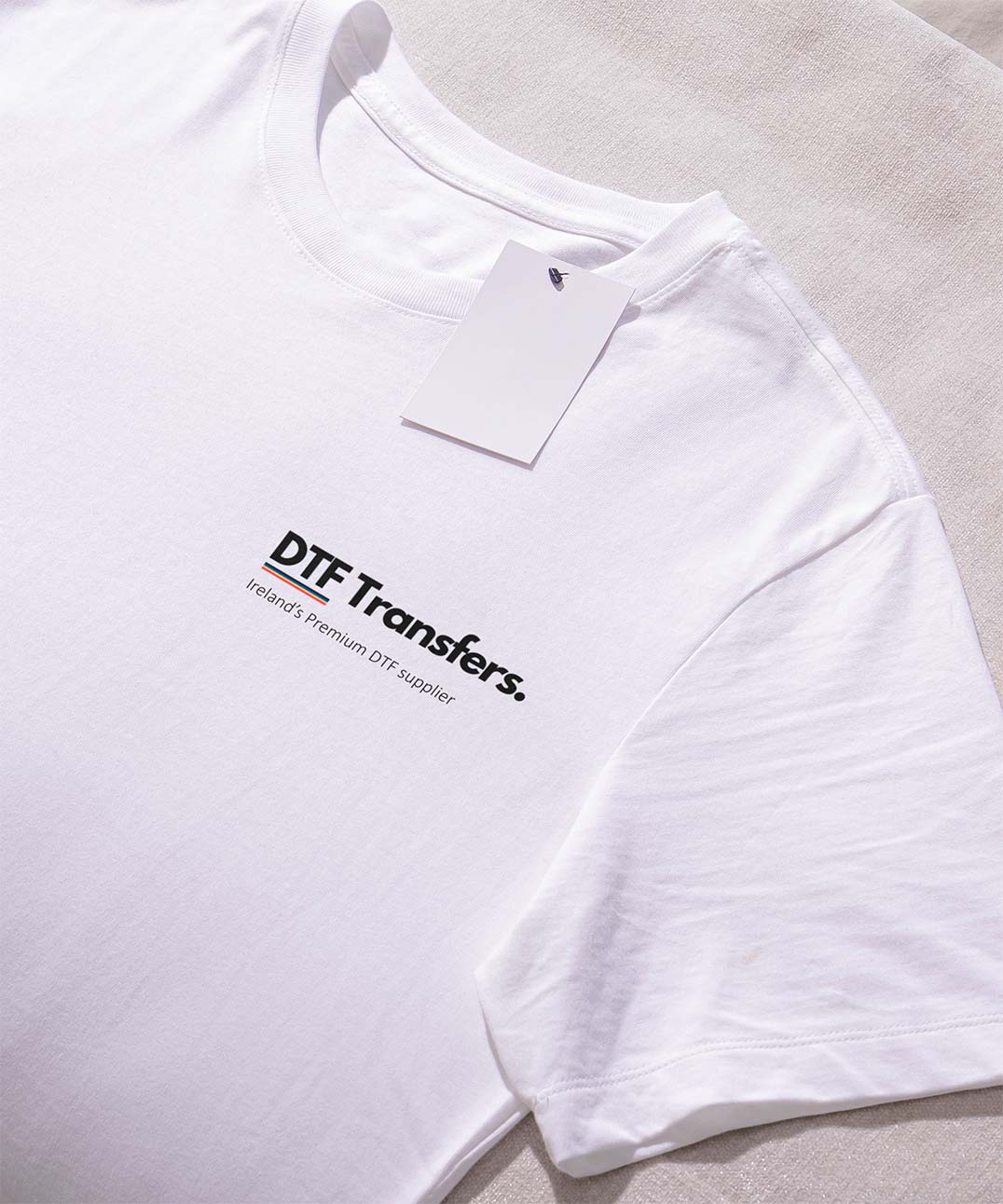 White shirt with 'DTF Transfers' logo prominently placed on the left breast, showcasing a clean and simple design.