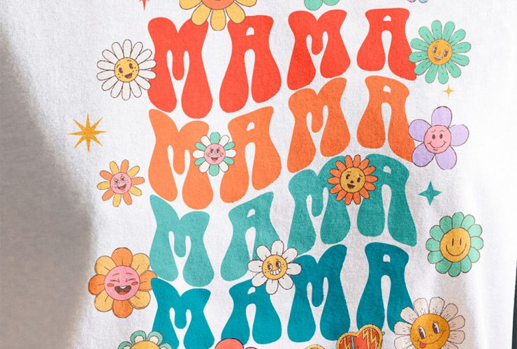 A woman wearing a white t-shirt customized with a DTF transfer of cartoon flowers and the word "Mama" in bright, vibrant colors.