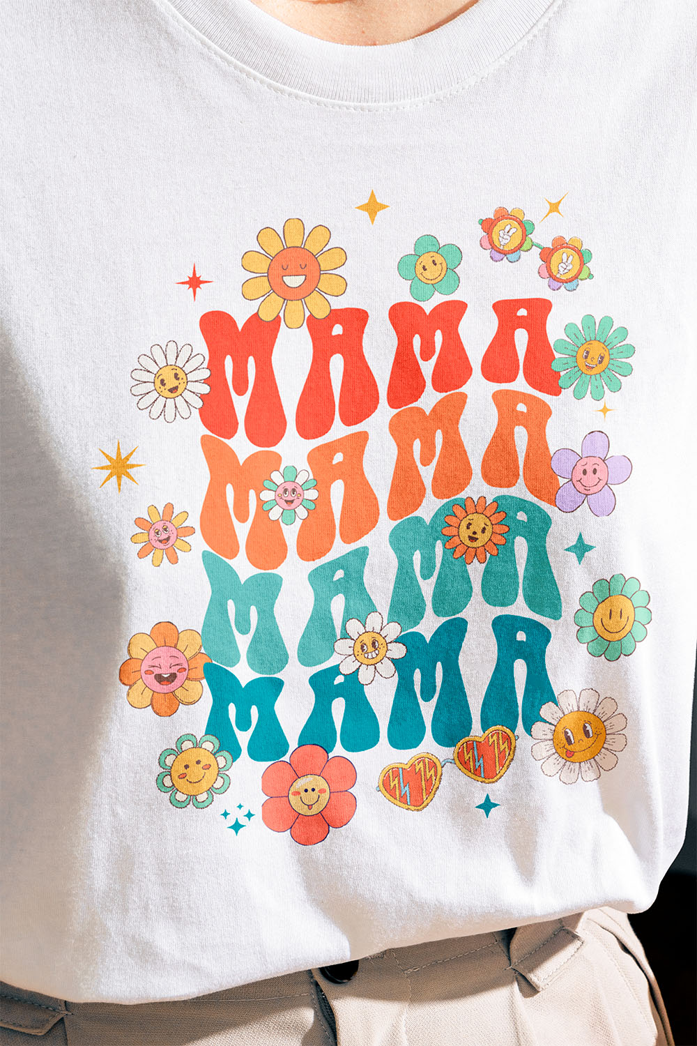 A woman wearing a white t-shirt customized with a DTF transfer of cartoon flowers and the word "Mama" in bright, vibrant colors.